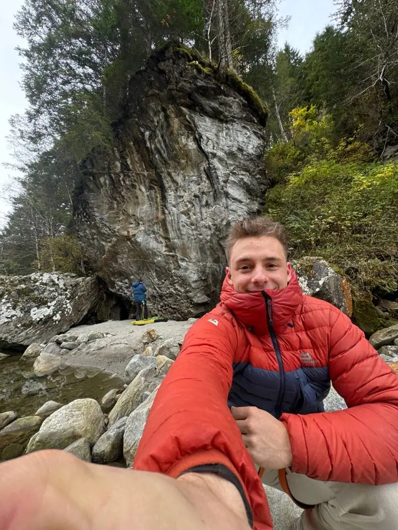 Trainer draußen am Fels in roter Daunenjacke